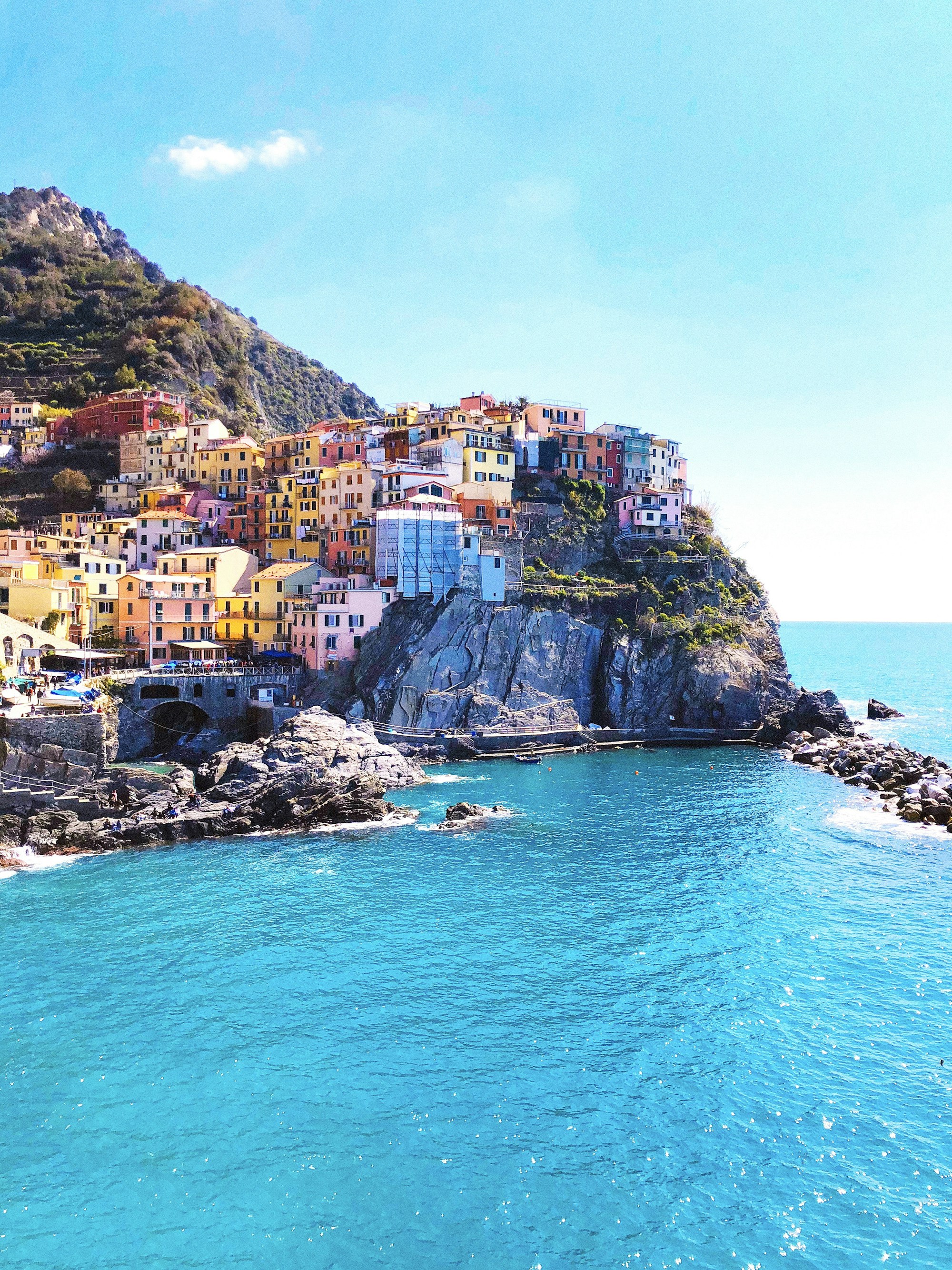 Sunlit colorful houses in Manarola overlooking the blue Mediterranean